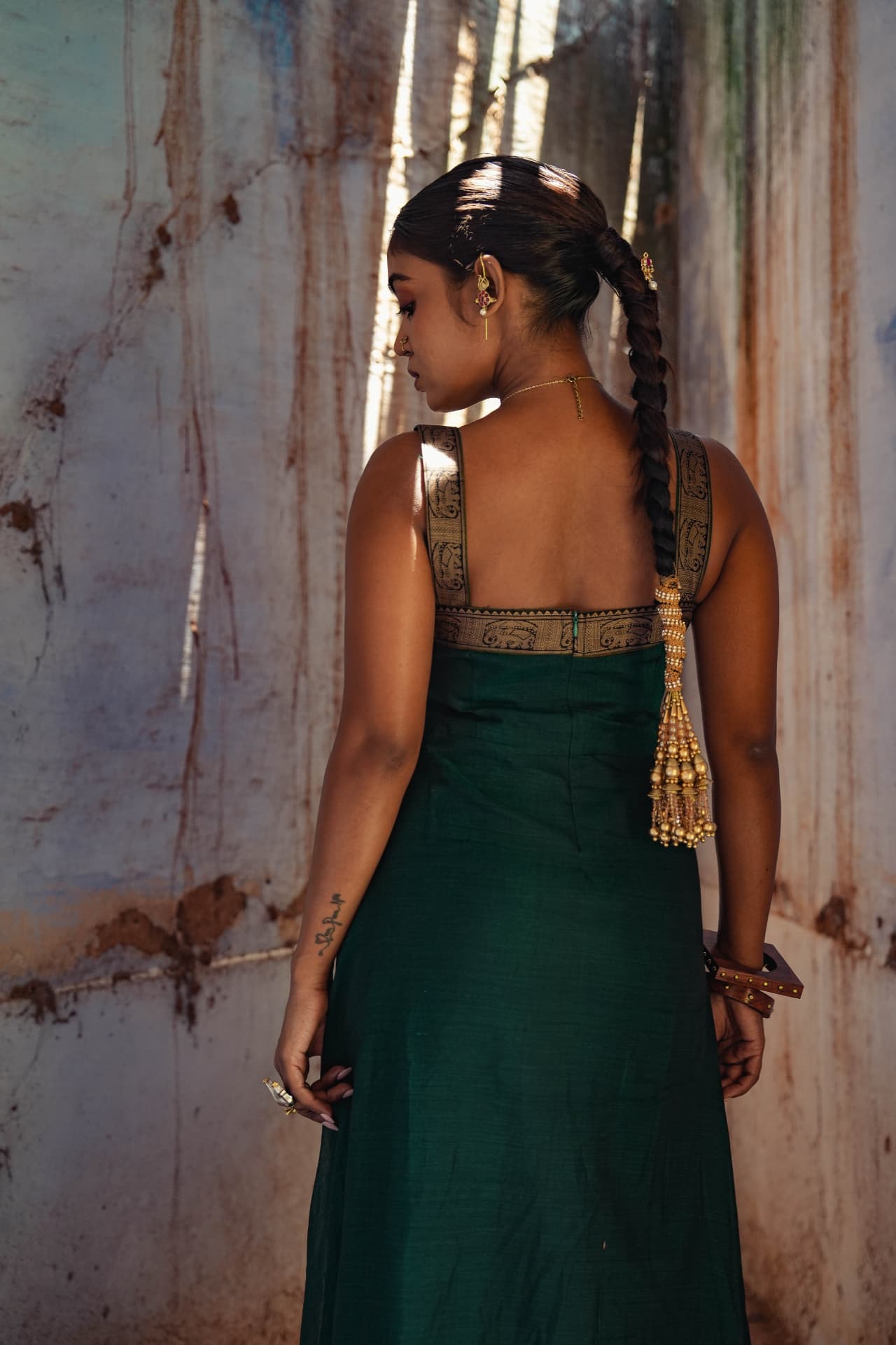 Emerald hand-embroidered gown against a textured heritage wall.