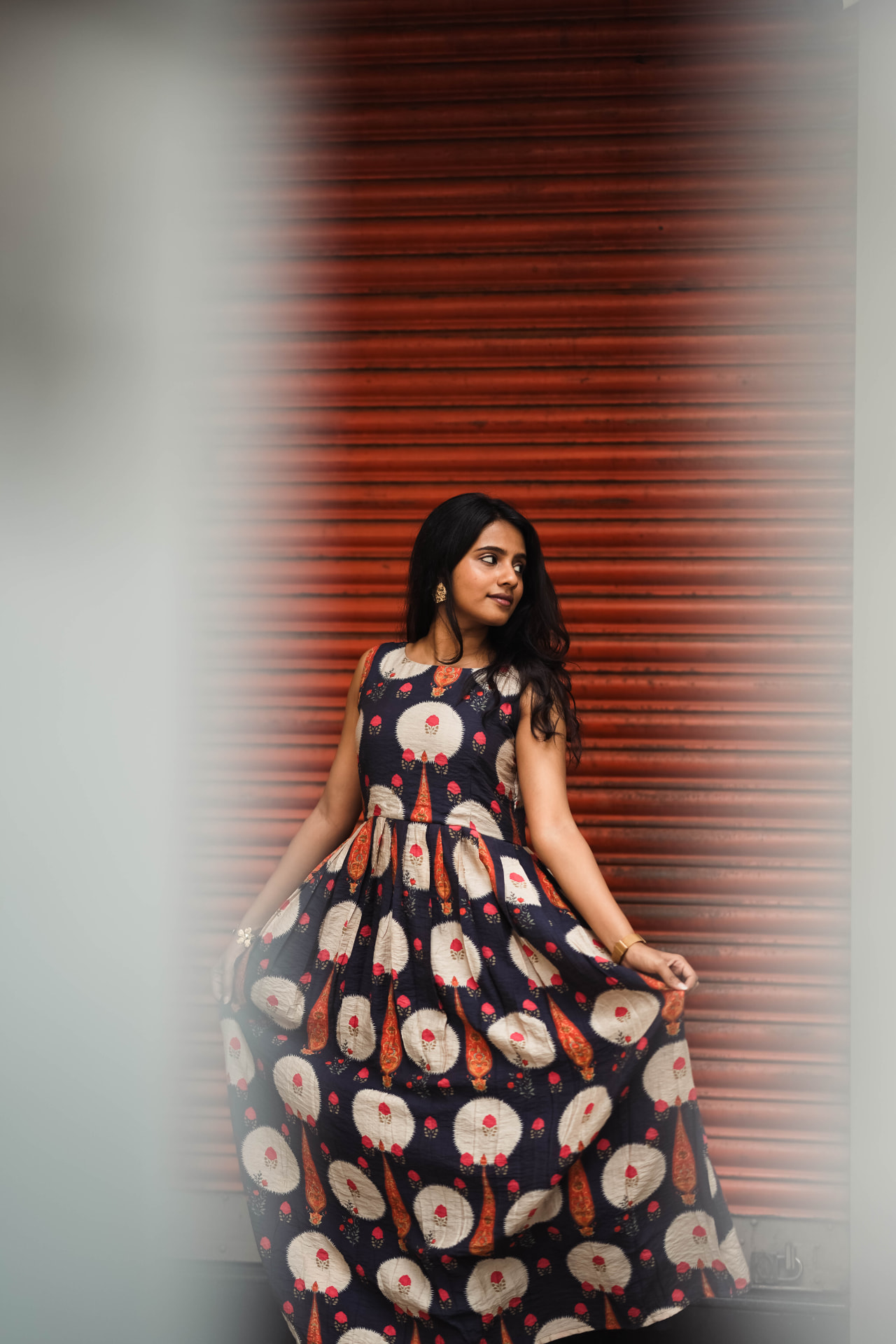 Model wearing a navy floral pleated dress with ivory motifs, photographed full length.