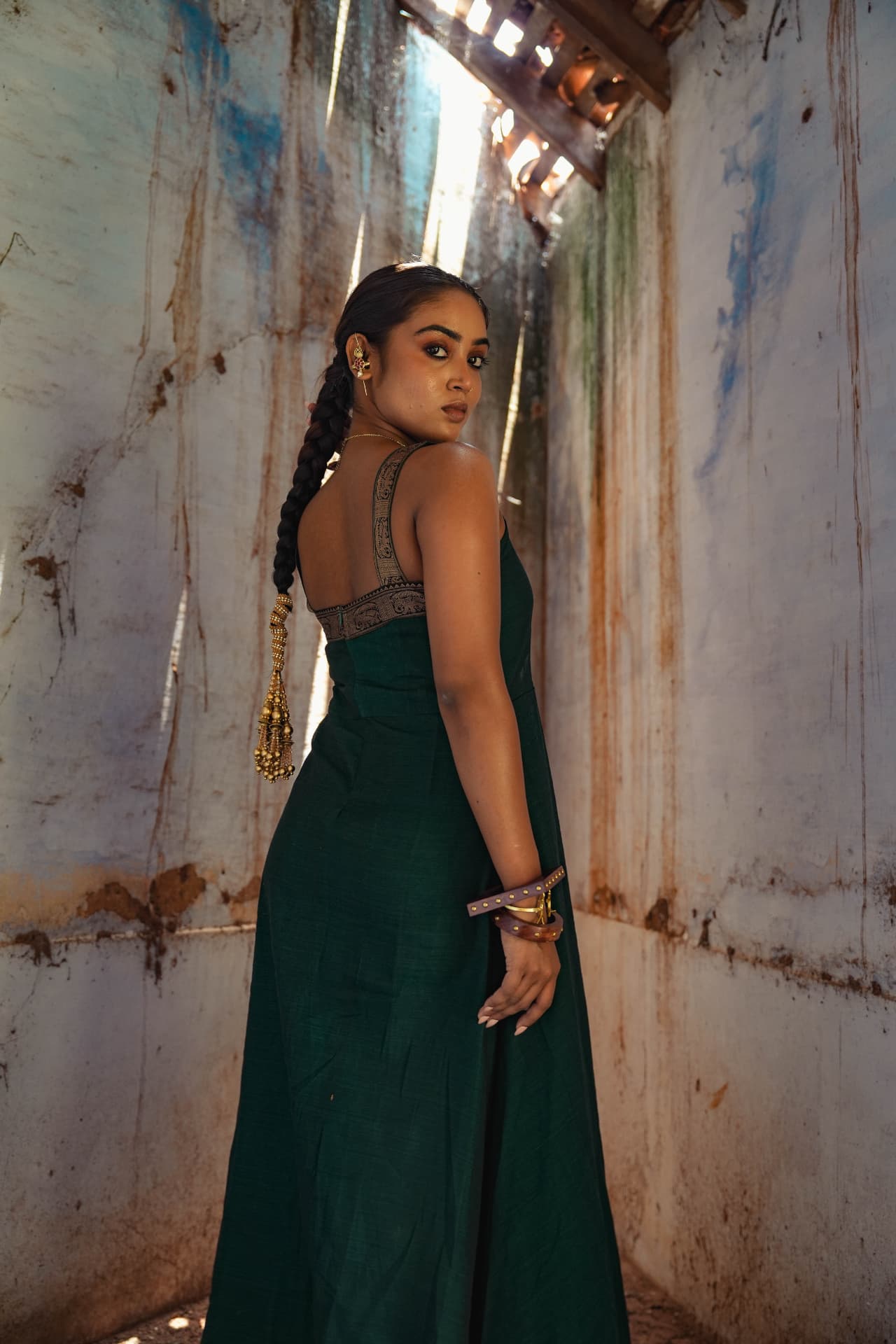Model in an emerald hand-embroidered gown, side profile.