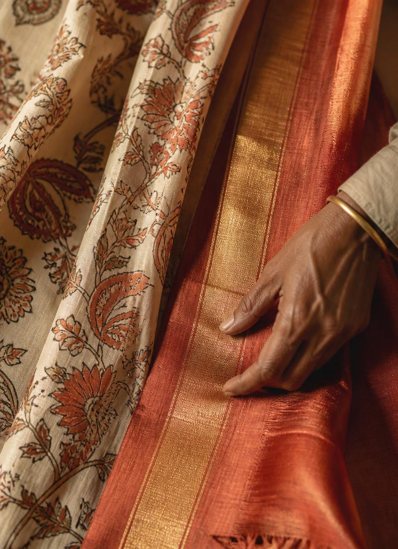 Hand resting on a rust and gold zari handloom silk drape next to kalamkari printed cotton.